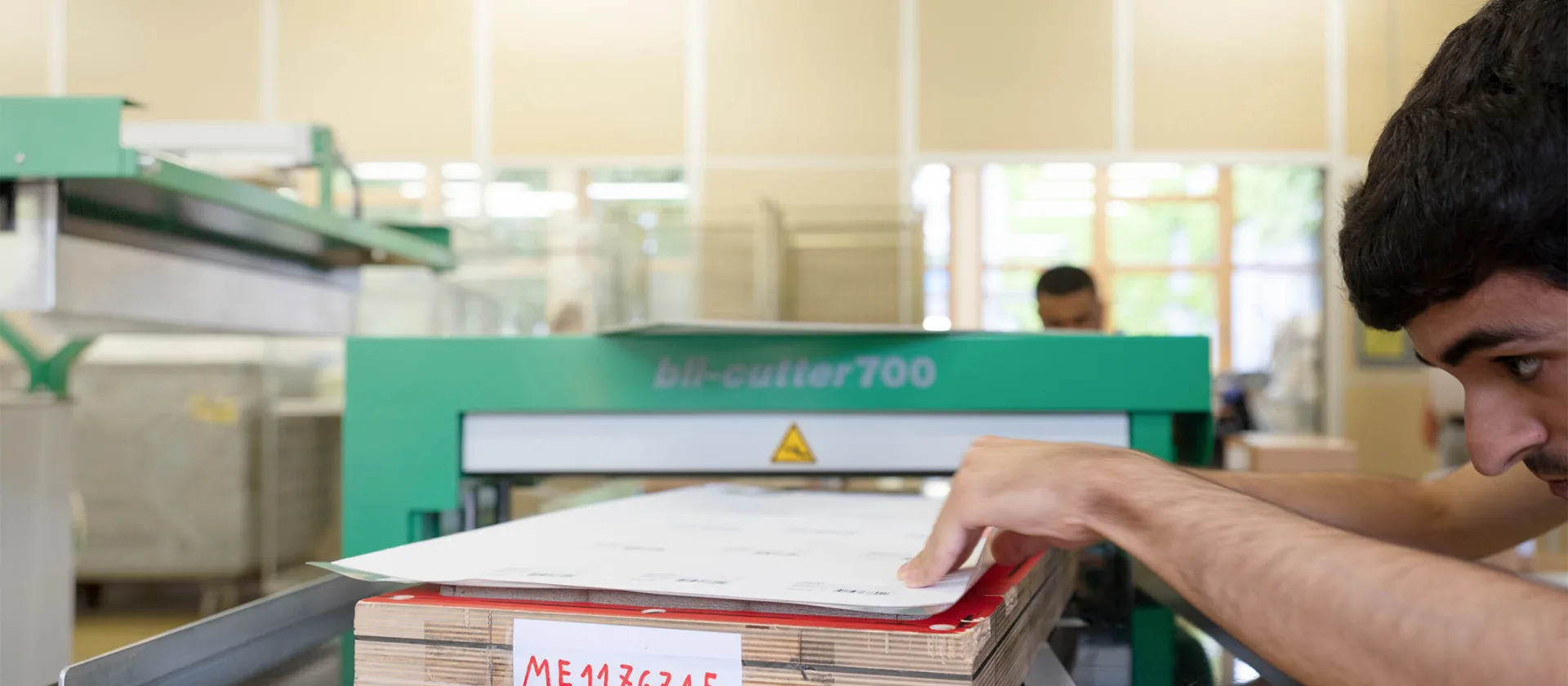 Eine Person in einer Werkstatt bedient eine Schneidemaschine